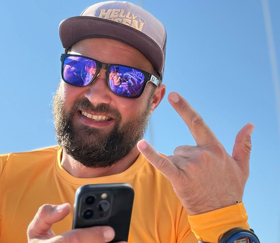 a man wearing sunglasses and a hat holding a phone